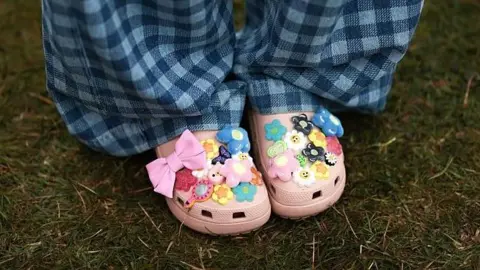 Getty Images Woman wears pink Croc clogs, adorned with different coloured charms